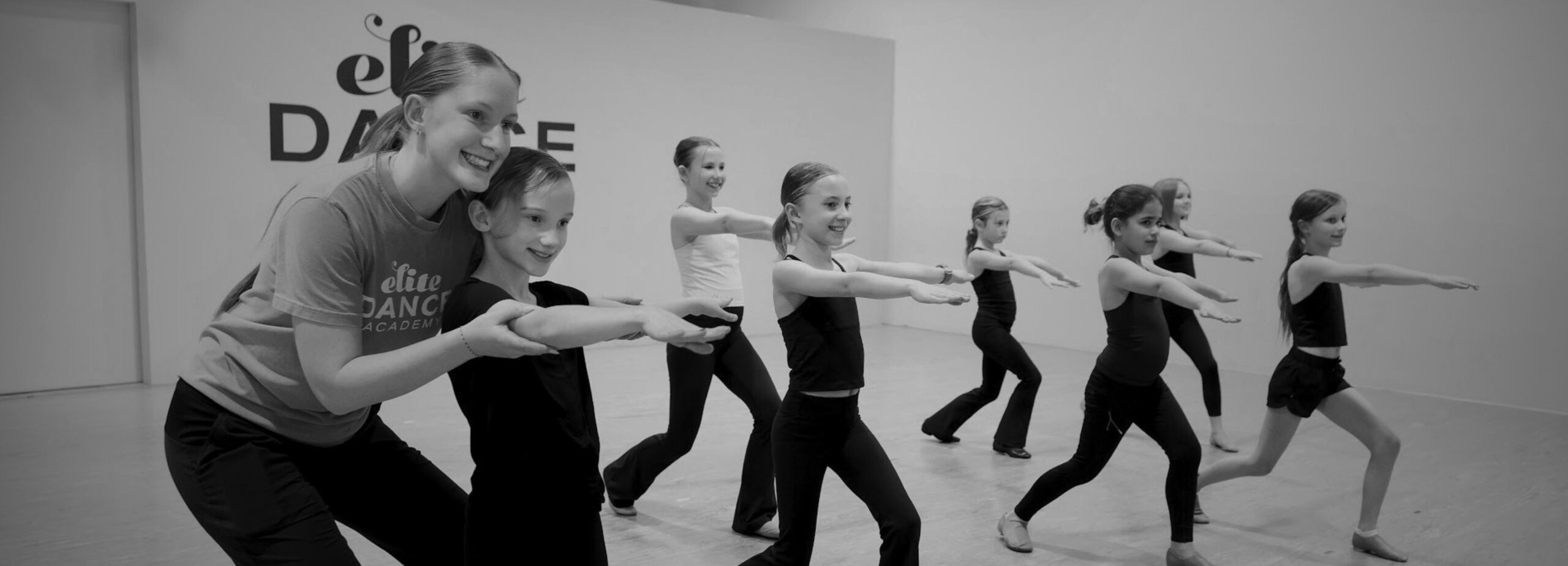 Three preschool dance students smiling while on the ground.
