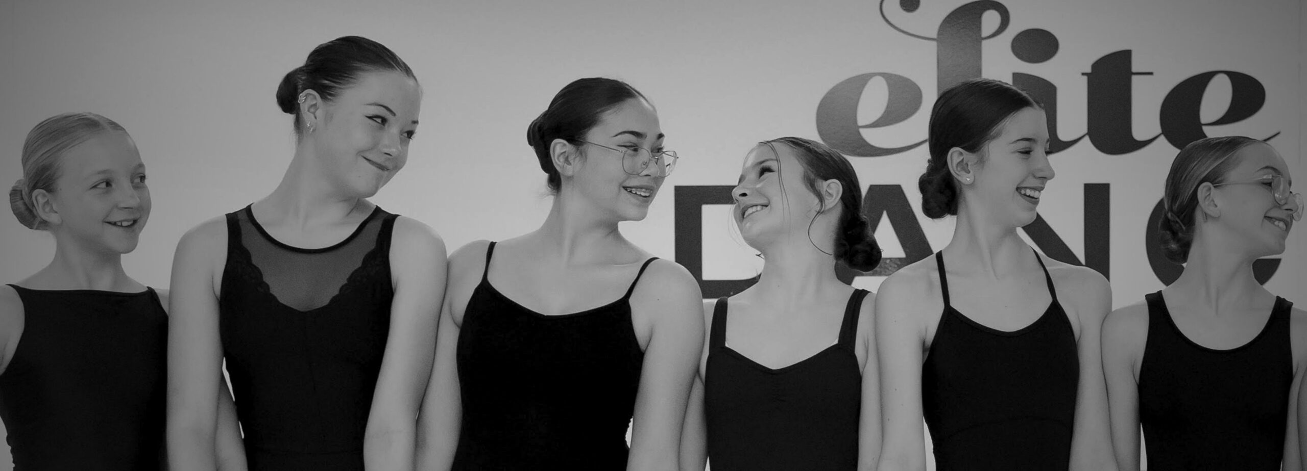 Three preschool dance students smiling while on the ground.