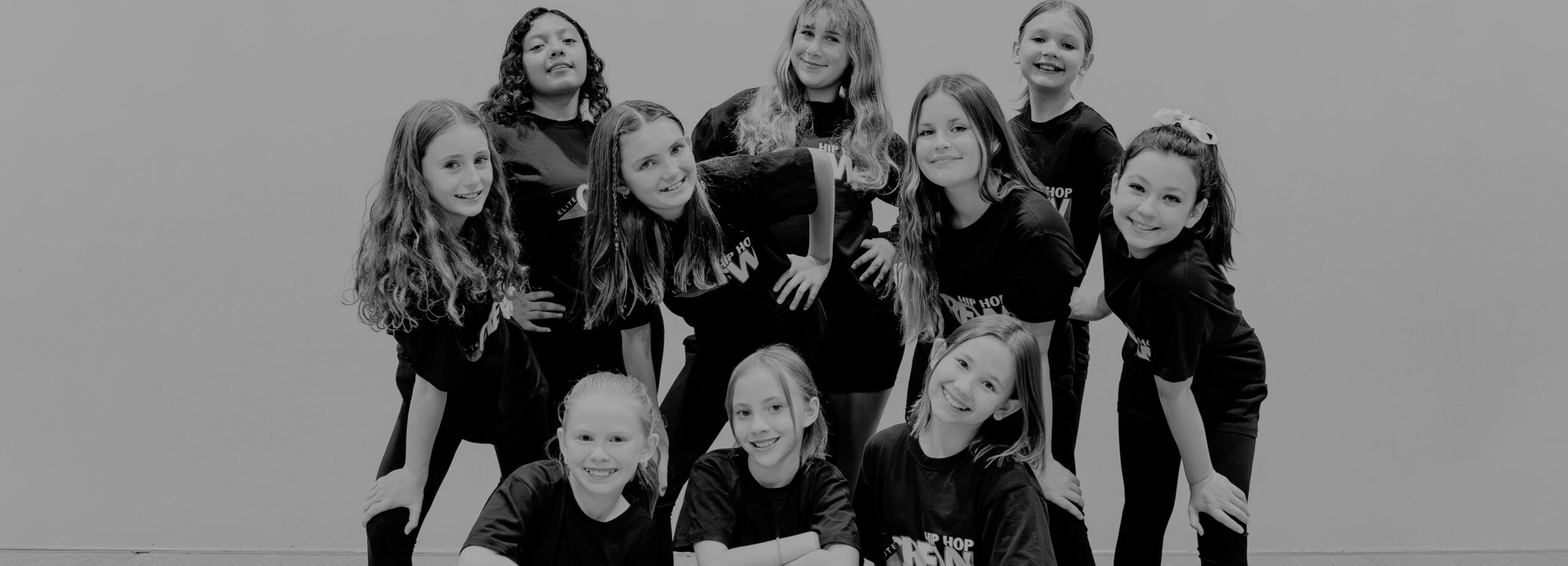 Three preschool dance students smiling while on the ground.