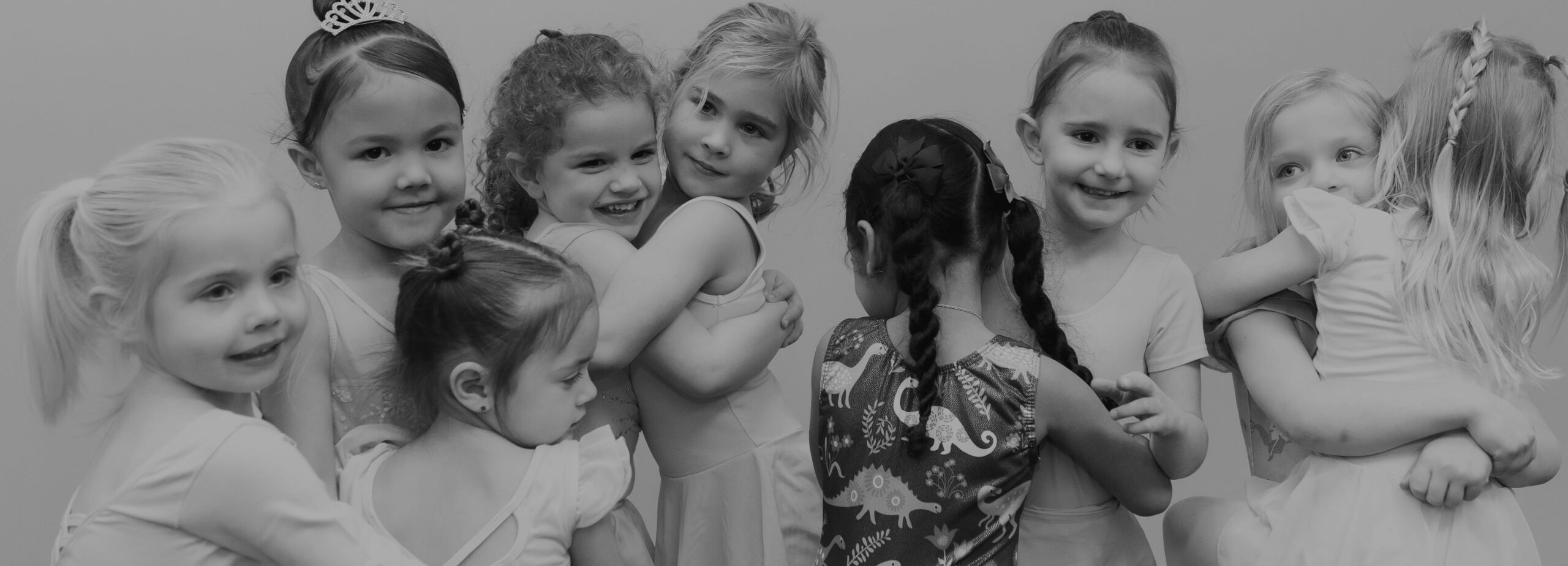 Three preschool dance students smiling while on the ground.